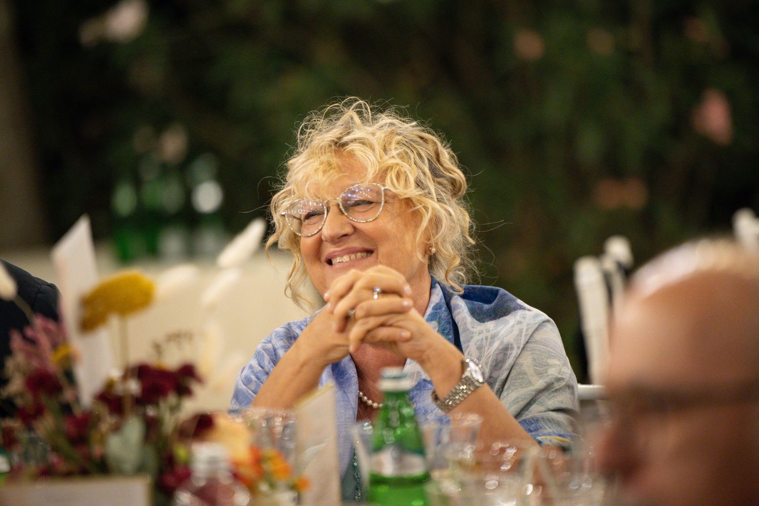 Wedding reception guests laughing and enjoying themselves at decorated outdoor dining tables.