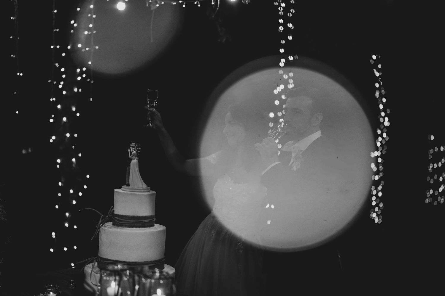 Black and white photo of a glowing dome light fixture against a dark ceiling with twinkling reflections.