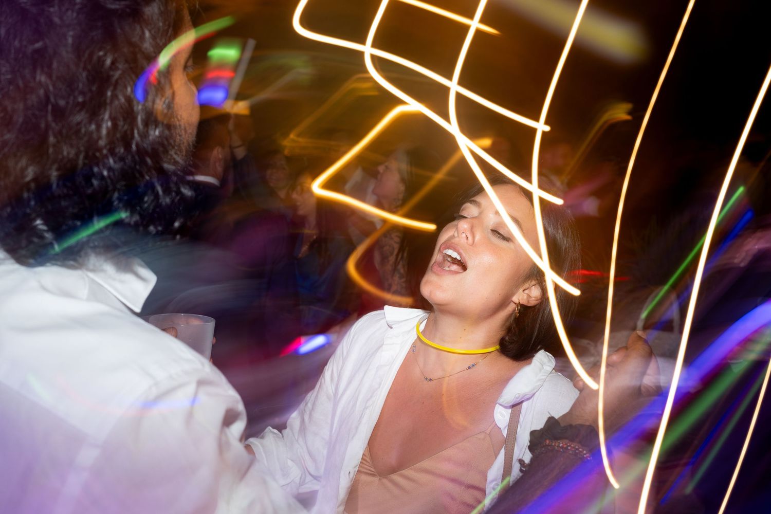 People dancing and having fun at a nightclub with colorful lighting and party atmosphere.