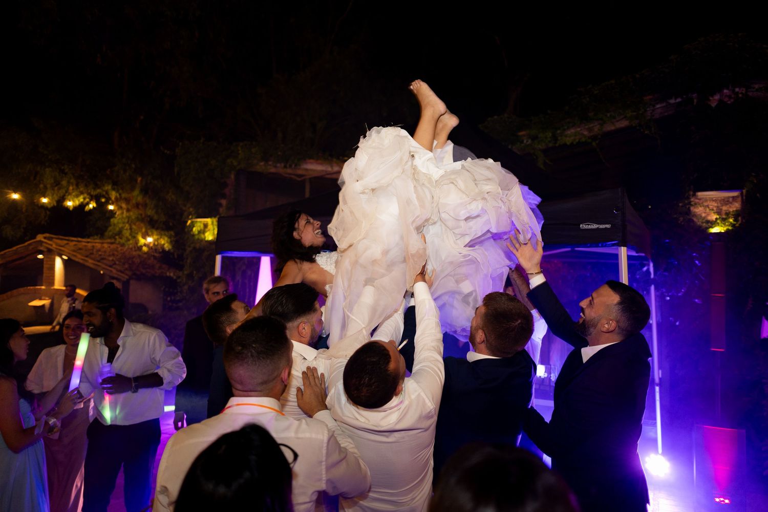 Wedding reception dance floor filled with guests celebrating under dramatic purple and blue lighting.