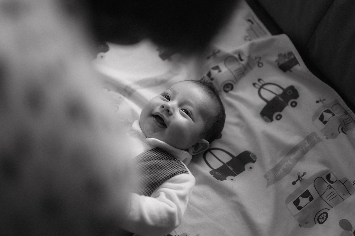 Peaceful black and white image of a sleeping baby on patterned bedding.