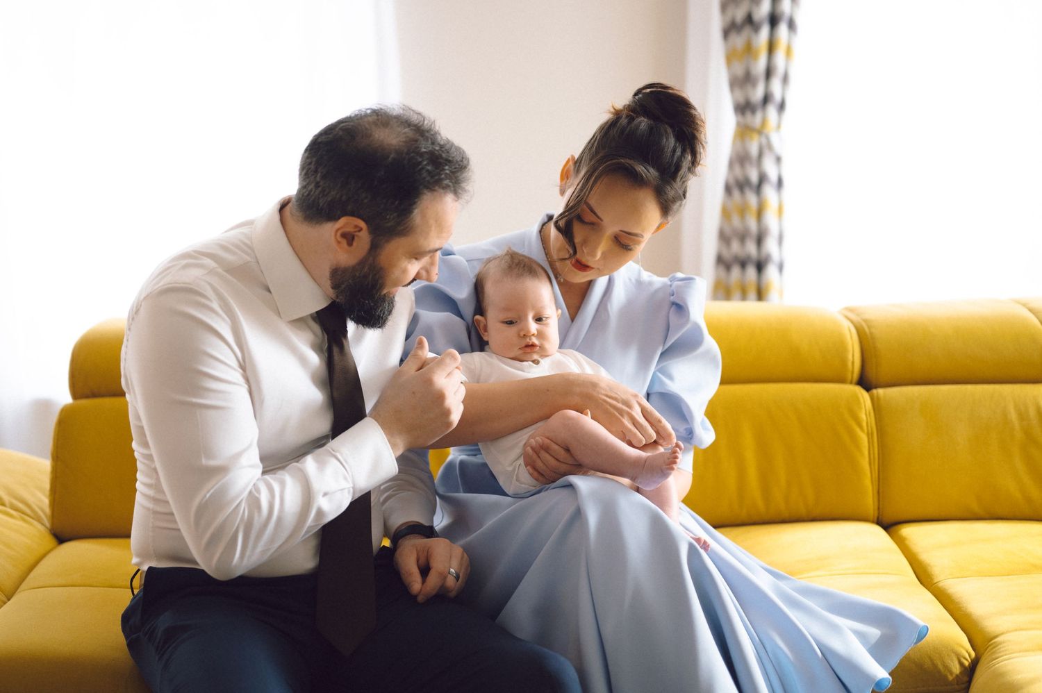 Family moment captured on yellow sofa in bright, modern living room setting.