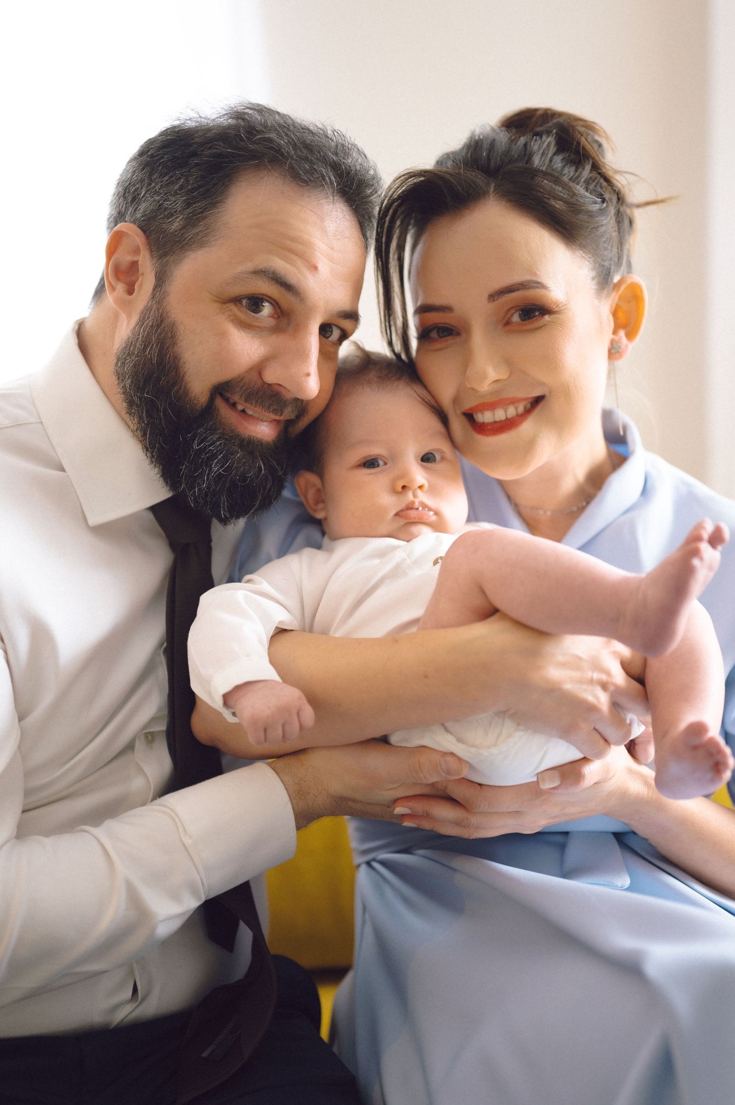 A family sitting together on a couch sharing a tender moment with their infant.