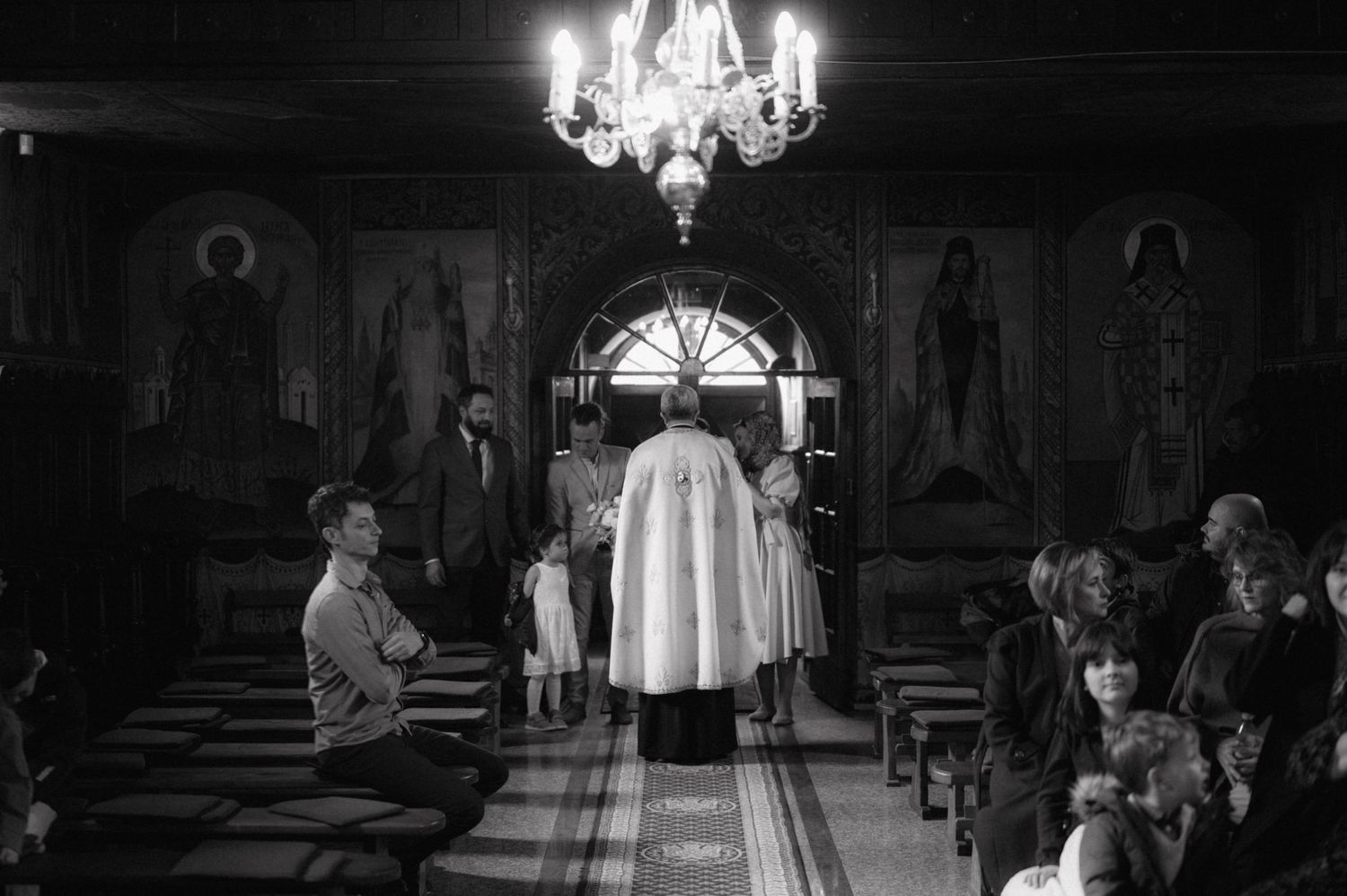 Black and white photo of traditional baptism ceremony in ornate church interior.