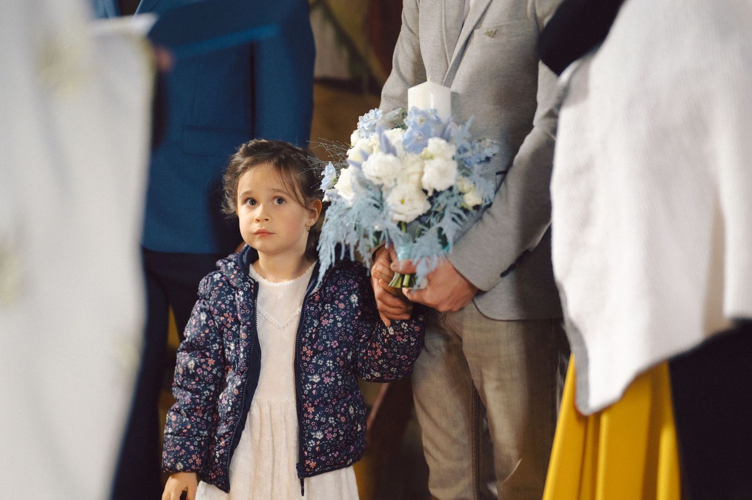 Child attending religious ceremony with decorative floral arrangements.