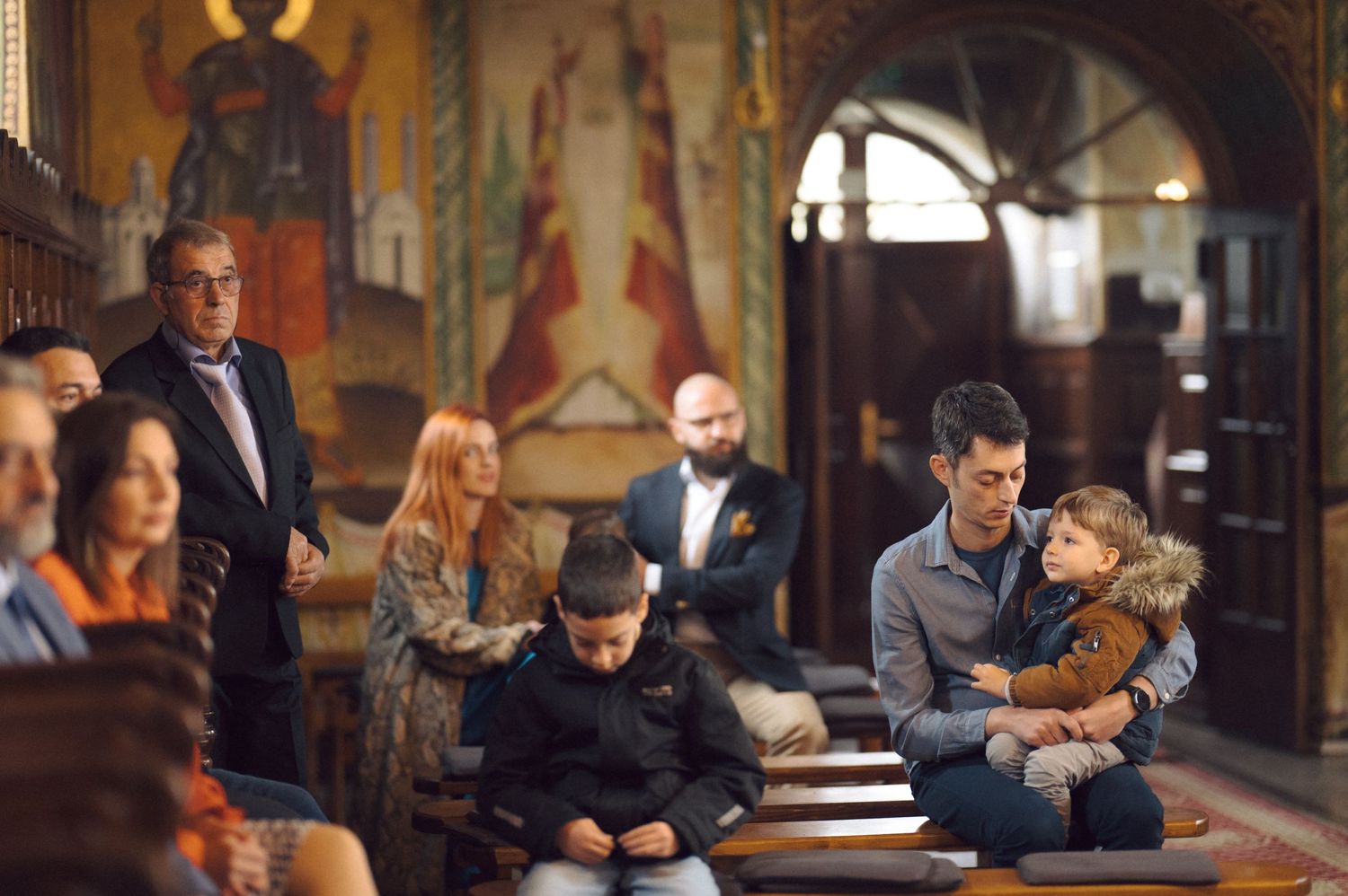 Families gathered in church pews during an Orthodox religious ceremony.