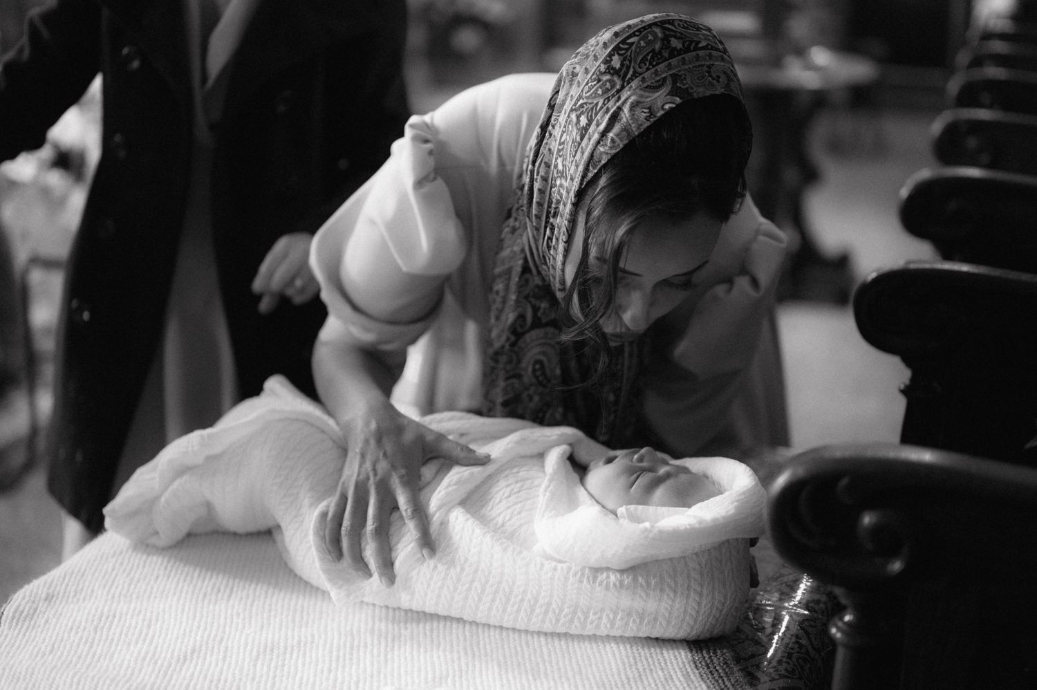 Person carefully handling white fabric during traditional ceremony preparation.