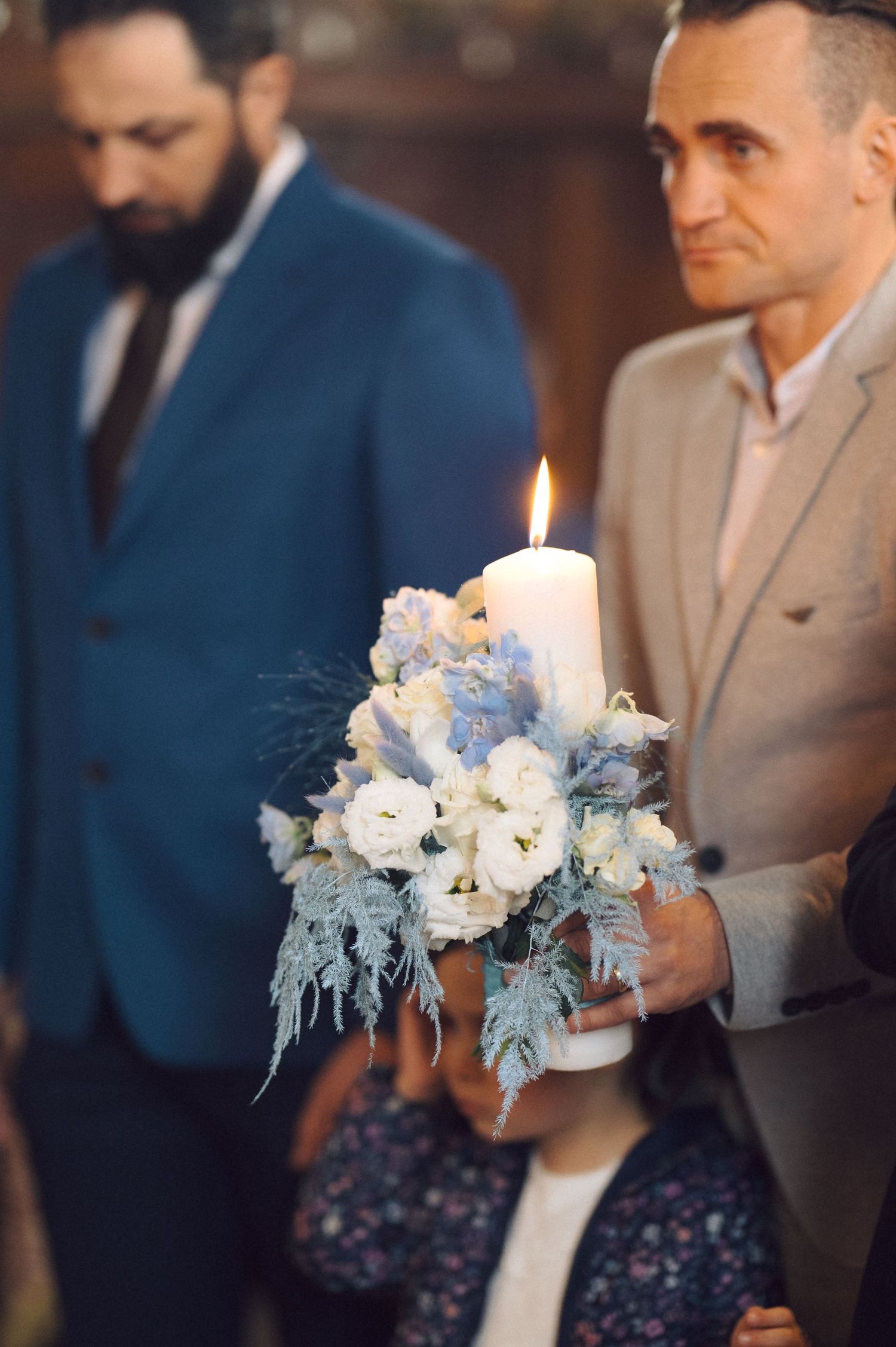 Decorative candle arrangement with white and blue flowers during ceremony.
