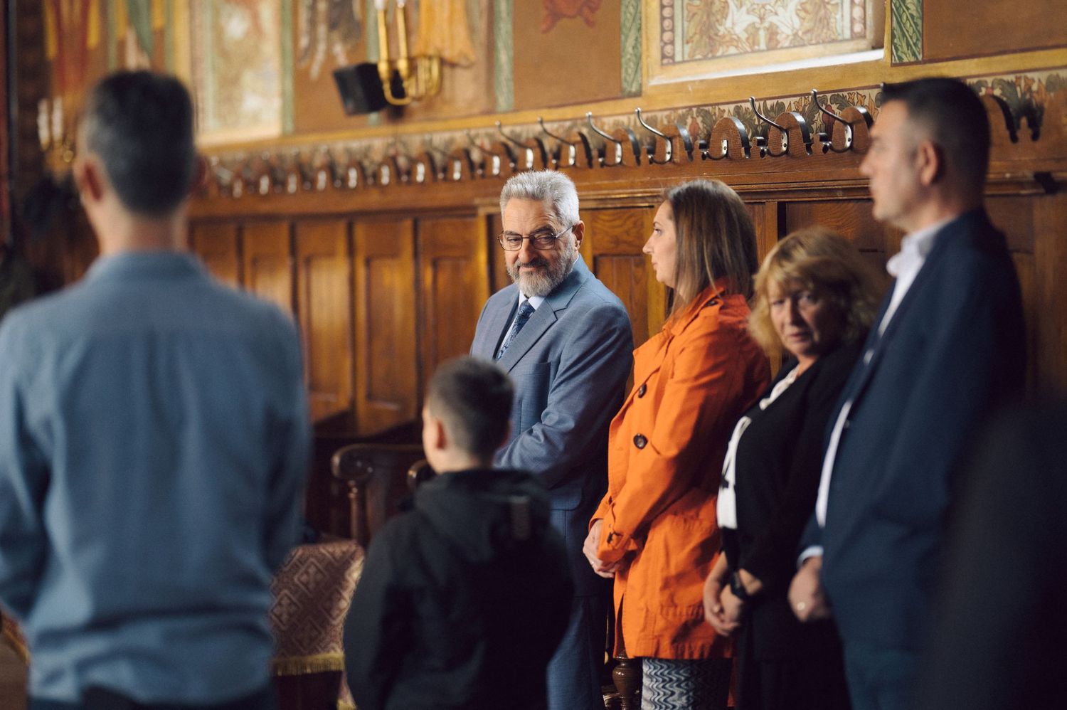 Group of people gathered inside a church with wooden paneled walls and decorative details.