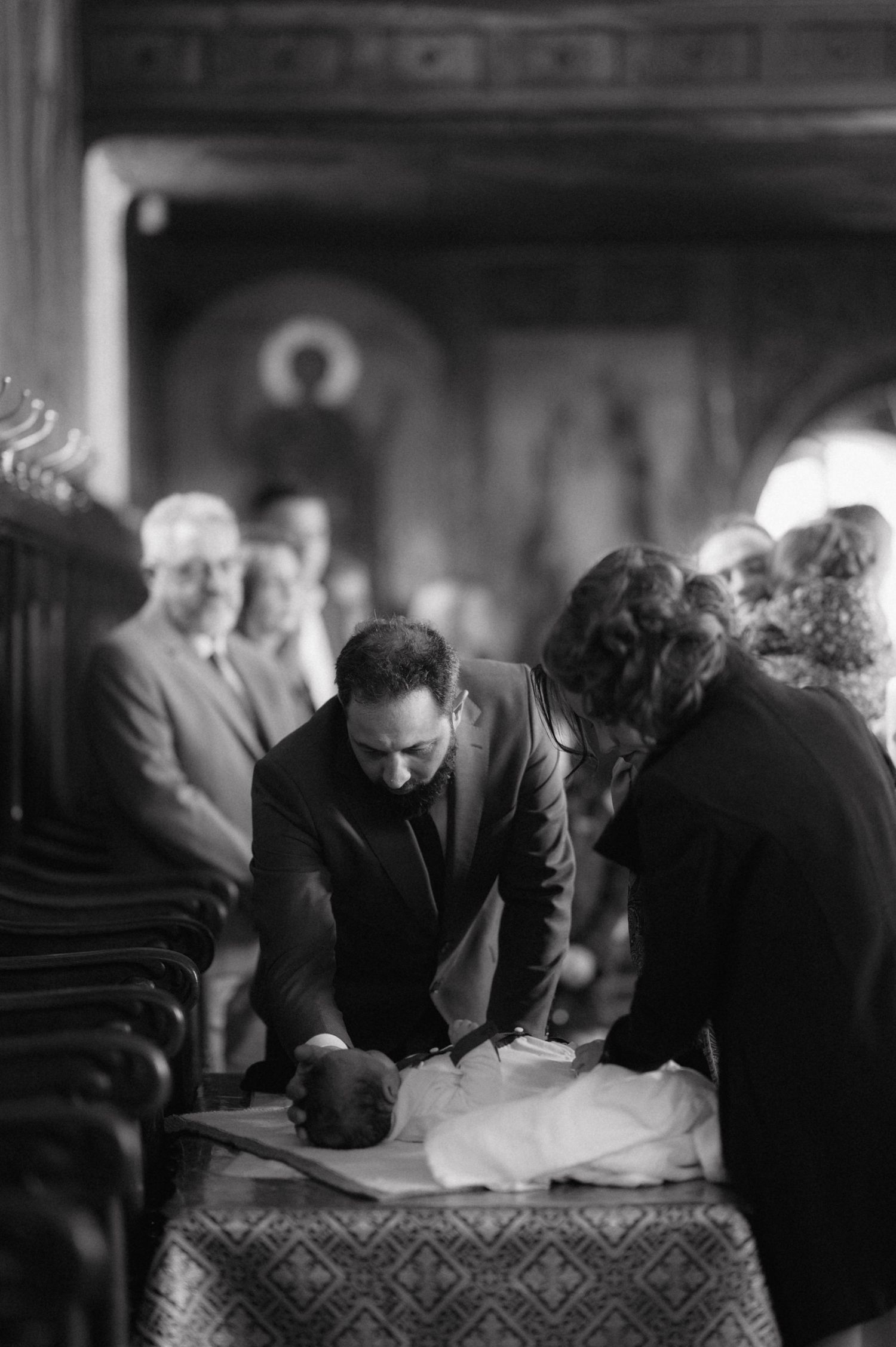 Black and white photo of a church ceremony with attendees gathered around a table.
