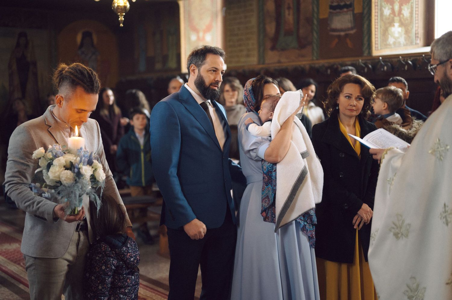 A wedding ceremony takes place inside an ornate church with guests gathered around the couple.