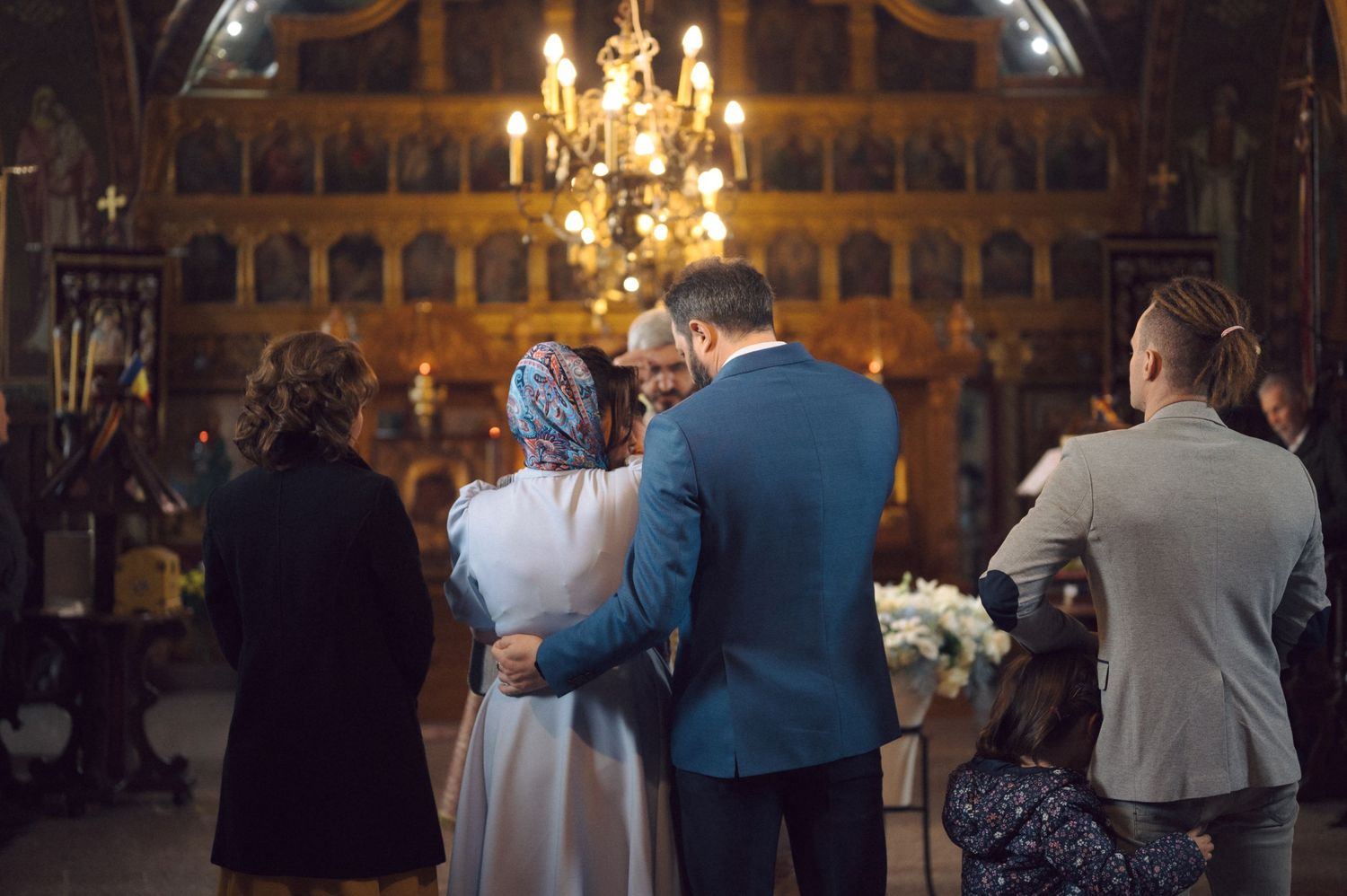 A small baby is held during a traditional baptism ceremony in a decorative church setting.