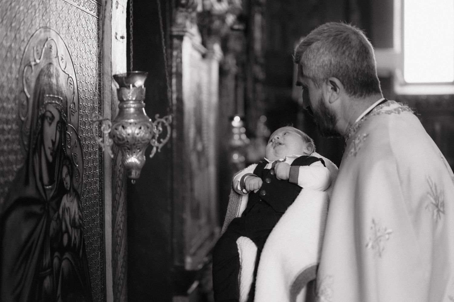 A black and white image captures an intimate moment during a religious ceremony in church.