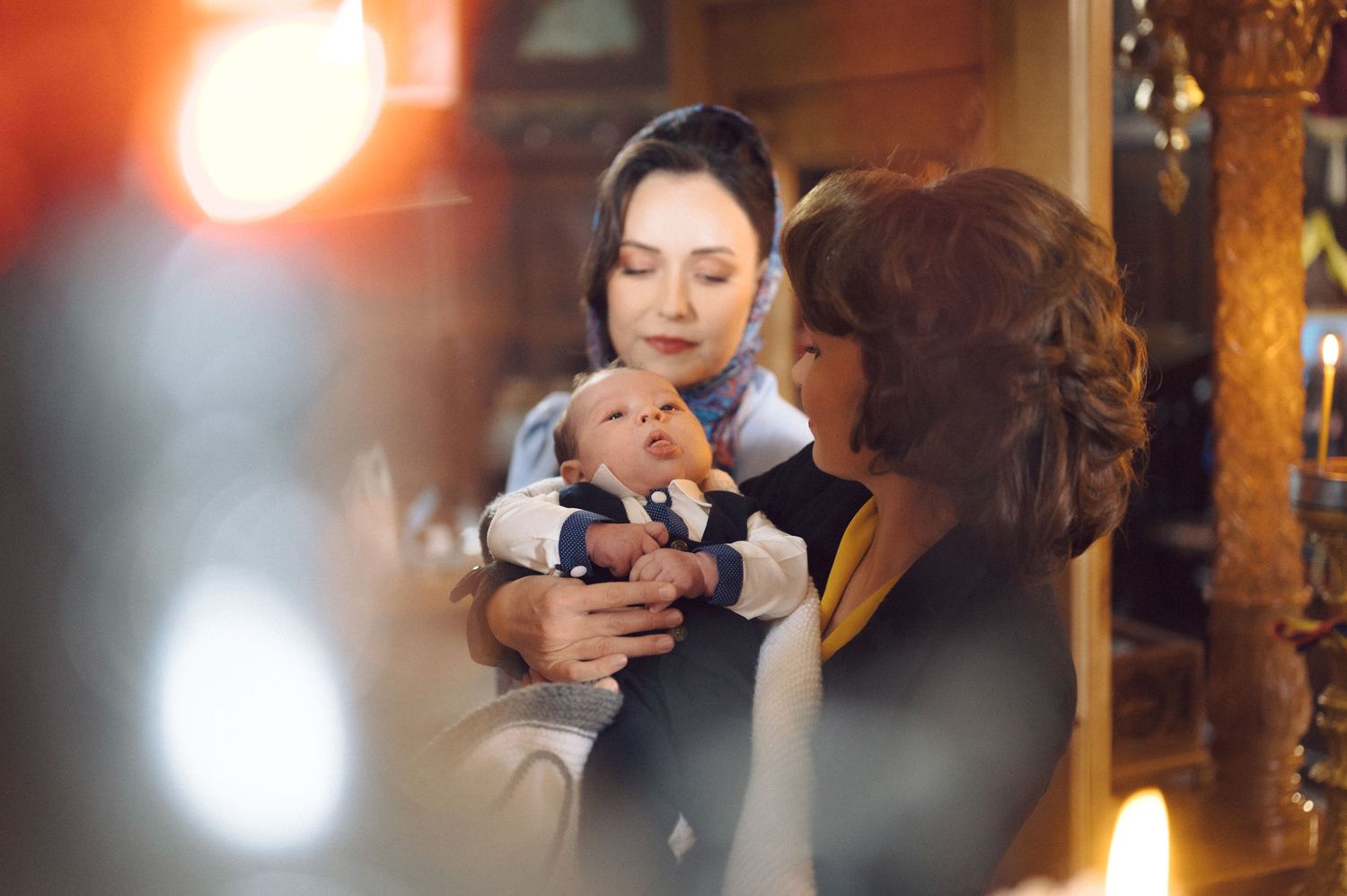 A traditional baptism ceremony is captured in warm lighting inside an ornate church.