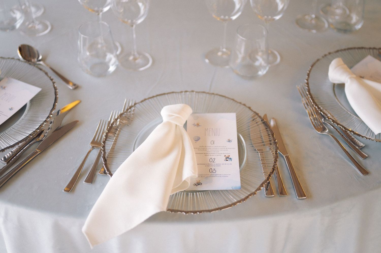 Elegant place setting with white napkin and gold charger plate on formal dining table.