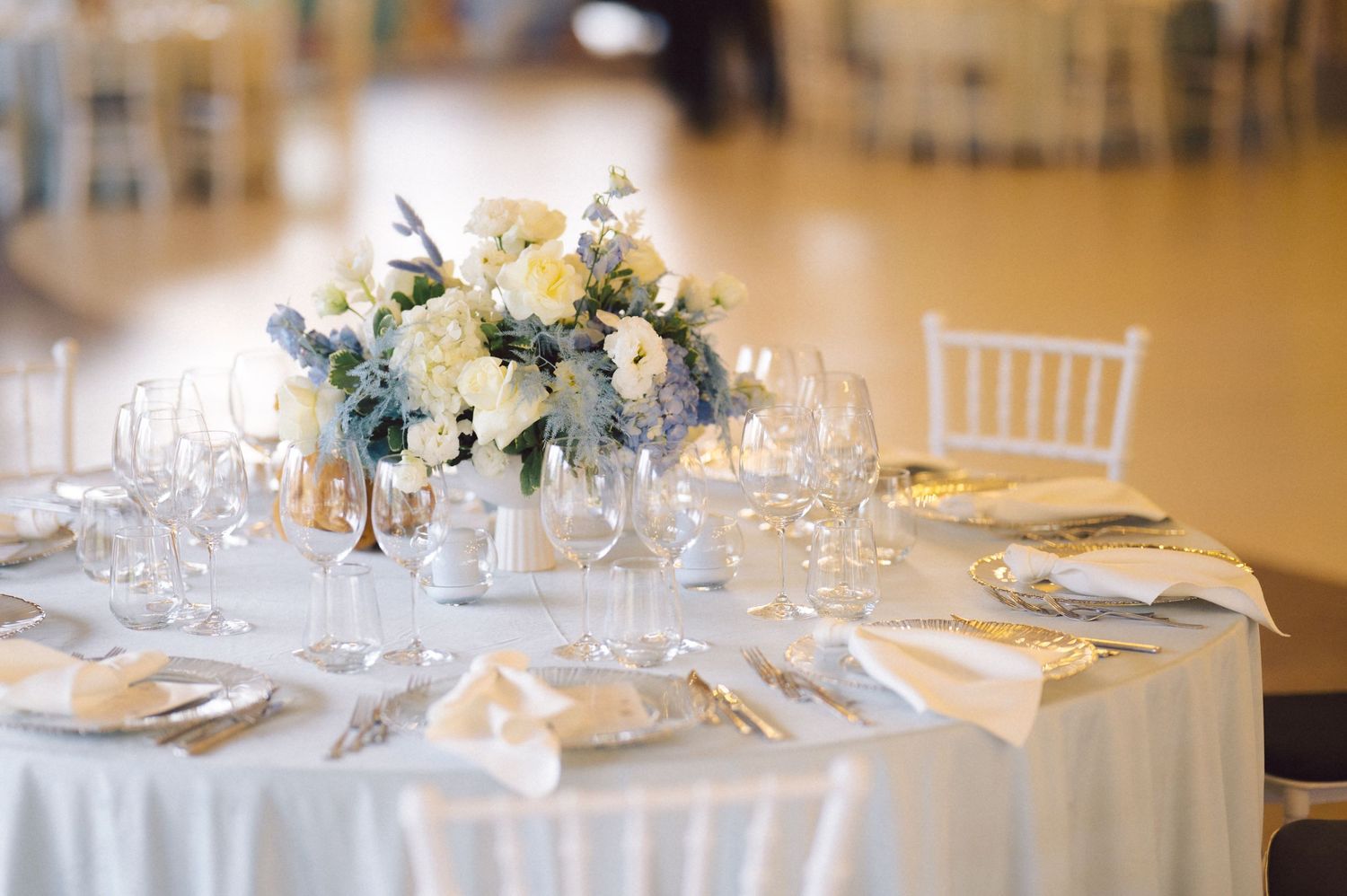 Elegant table setting with white and yellow flower centerpiece and crystal glassware.
