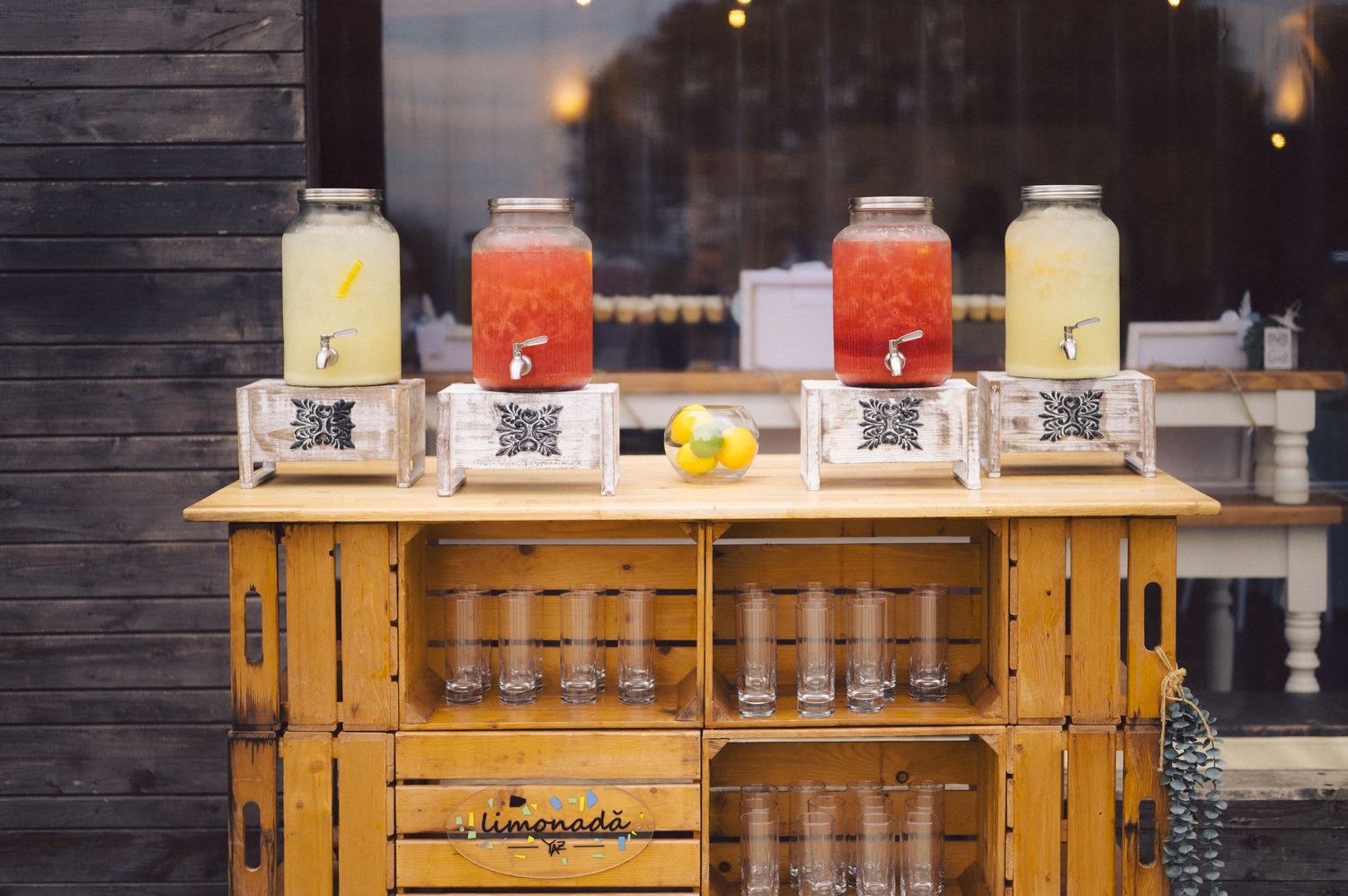 Rustic wooden drink station displays various beverage dispensers at outdoor event.