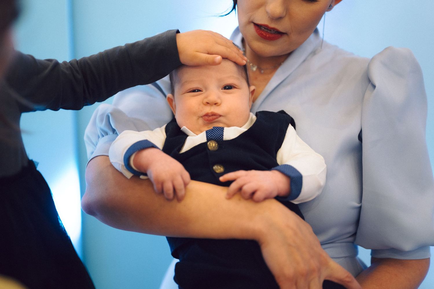 Baby wearing formal navy outfit at celebration event.