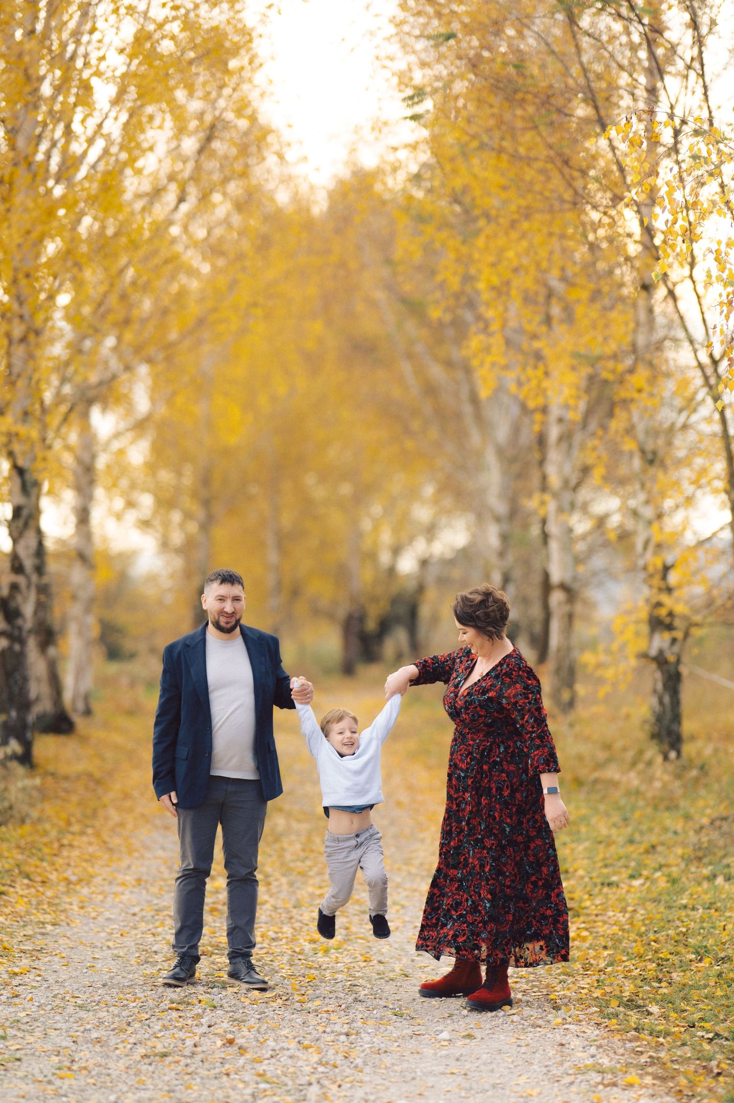 Family moment captured on a path surrounded by golden autumn trees.