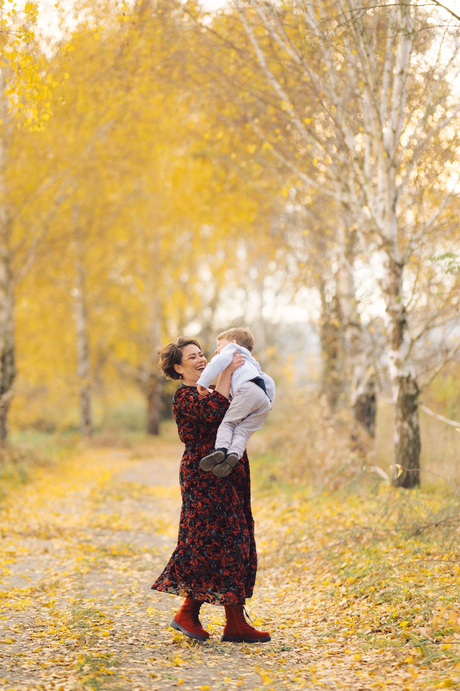 A pair embraces while standing among yellow autumn birch trees on a beautiful fall day.