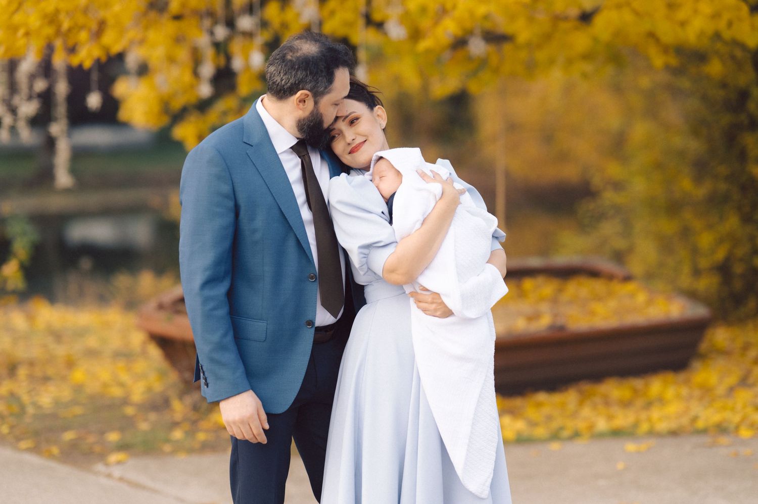 A couple shares an intimate moment outdoors against vibrant yellow fall foliage.