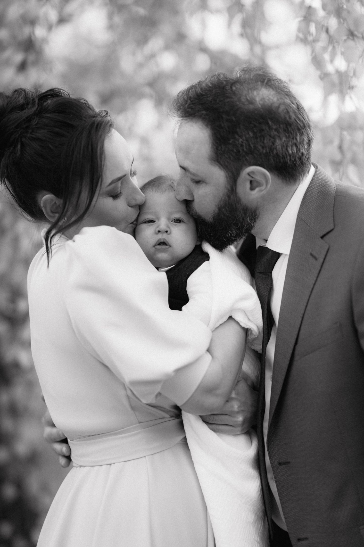 Black and white intimate family moment with baby between parents.
