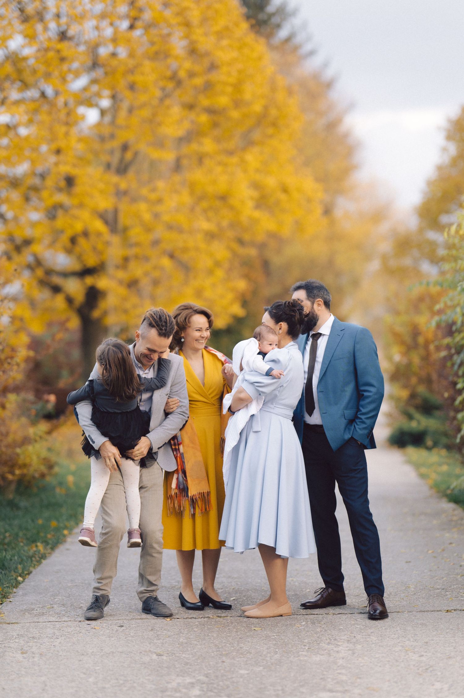 Group of people standing together on path with vibrant yellow autumn trees.