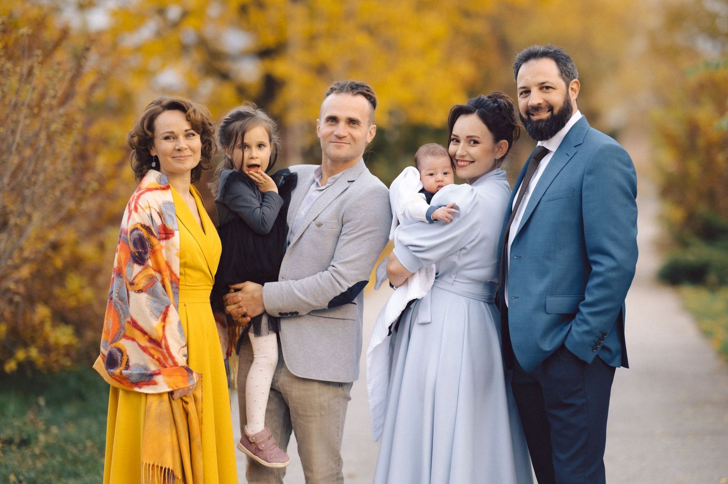 Group photo of families together on autumn path with yellow trees.
