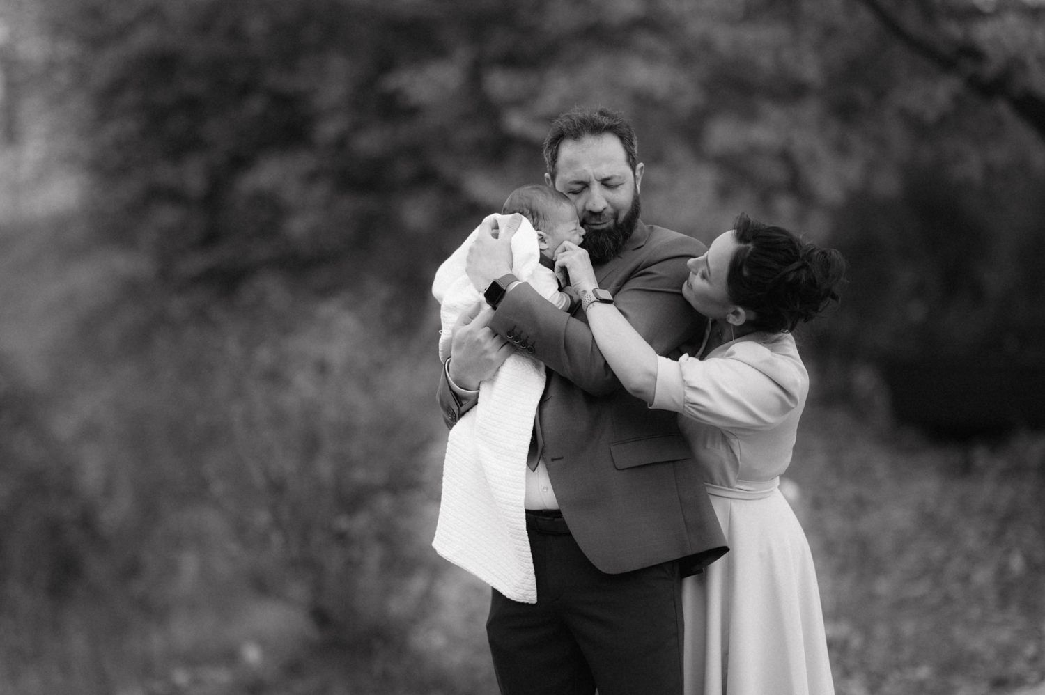 Black and white tender family moment outdoors.
