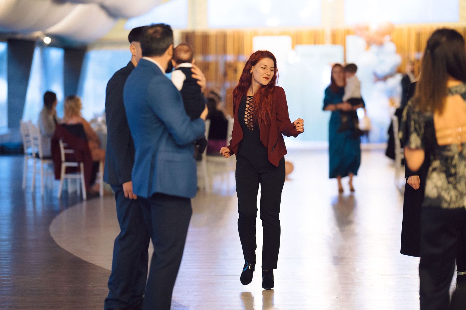 People interact at indoor event space with blurred figures in background.