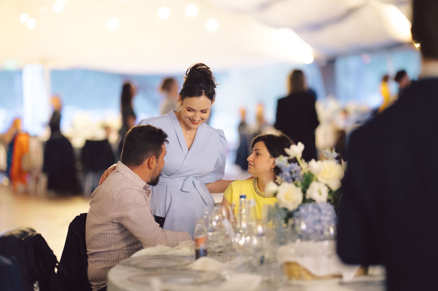 A server in gray attends to guests at an elegant table setting during a celebration.