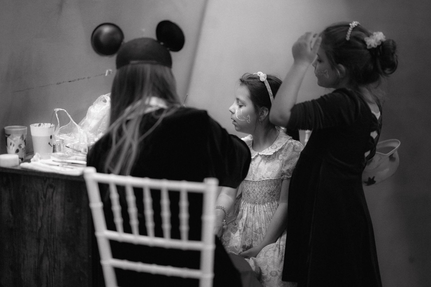 Children in formal attire gather around a table wearing Mickey Mouse ears.