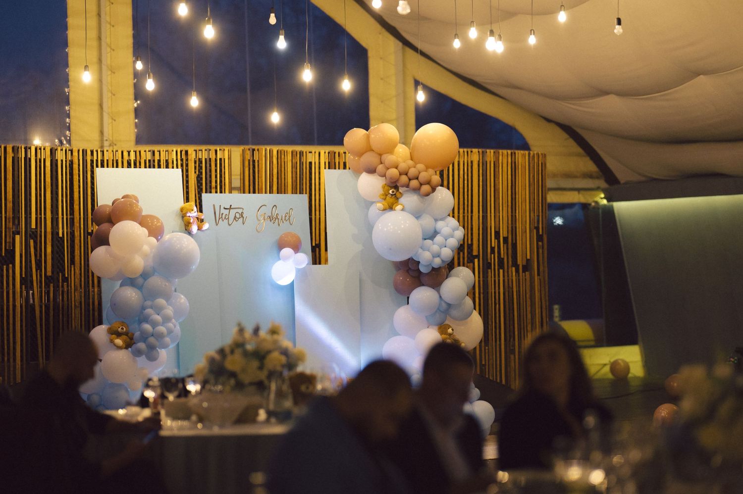 An elegant event space decorated with balloon arches and string lights creates a festive atmosphere.