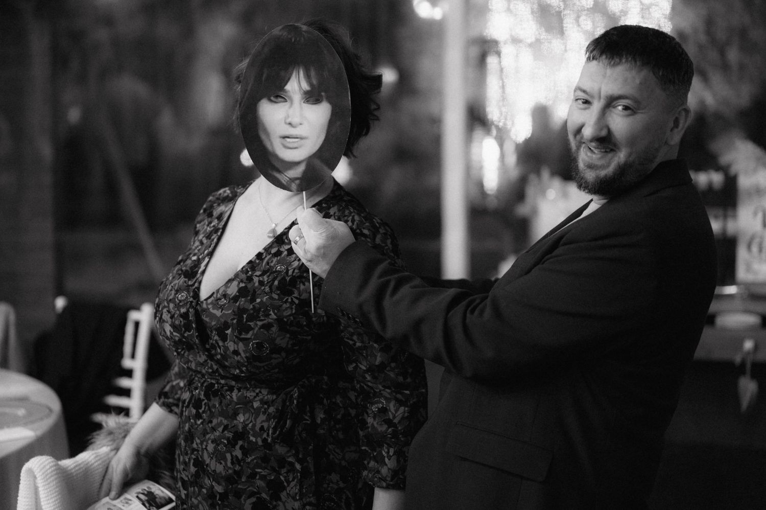 Black and white photo of two people posing together in a dimly lit space.