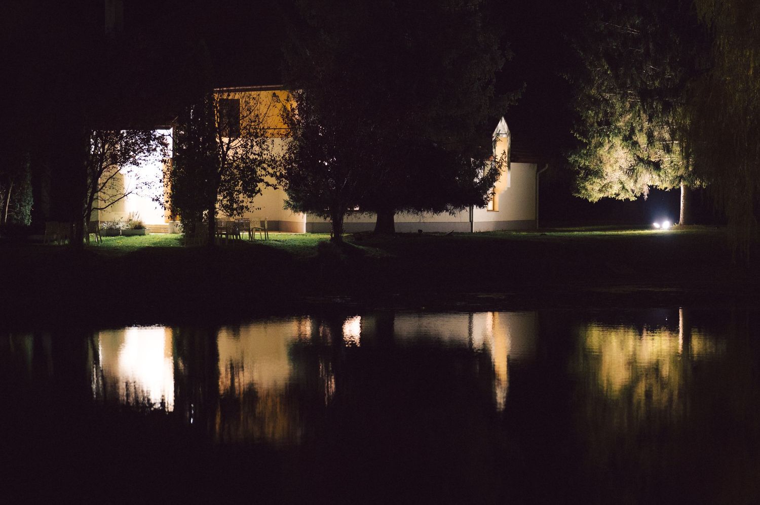 Night scene of buildings reflected in still water with illuminated structures.