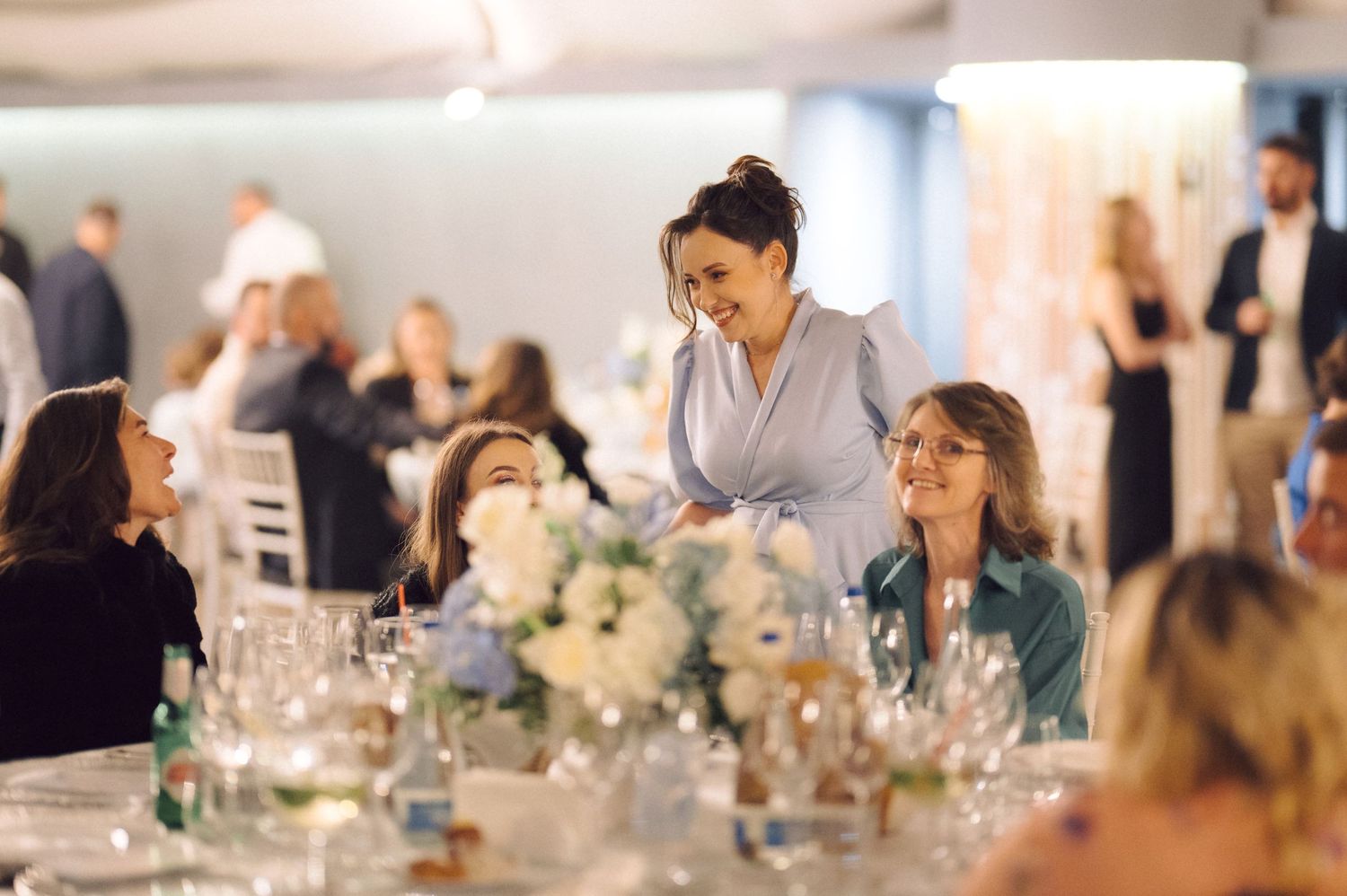 Wedding reception scene with elegant table settings and floral centerpieces.
