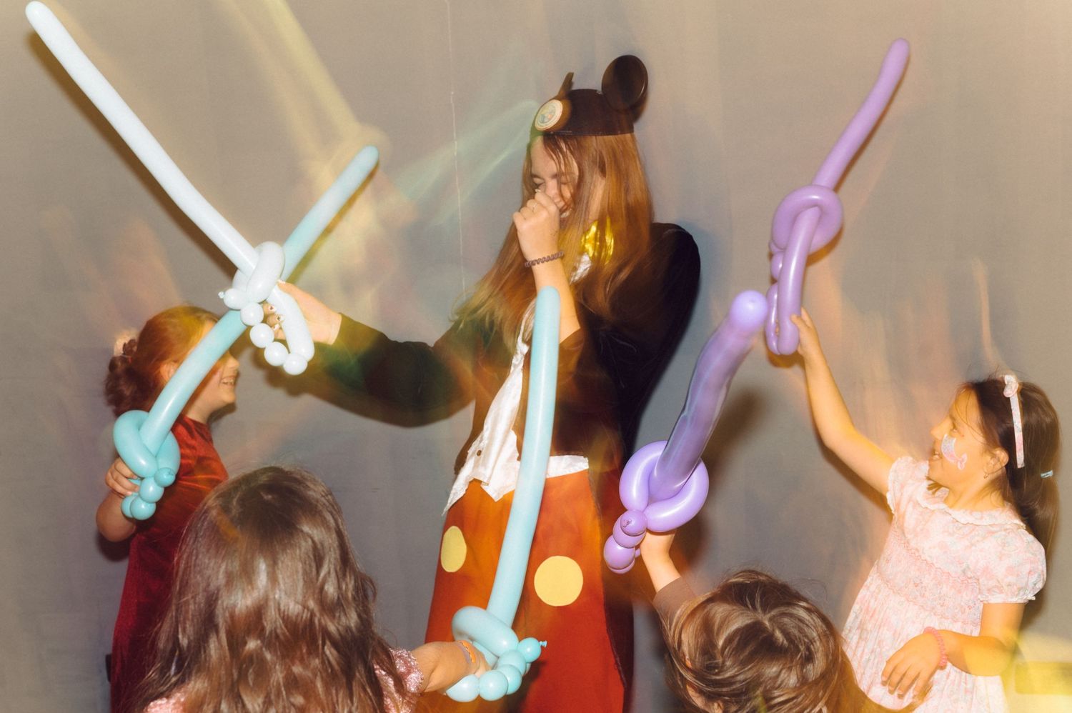 Group playing with colorful balloon swords at indoor celebration.