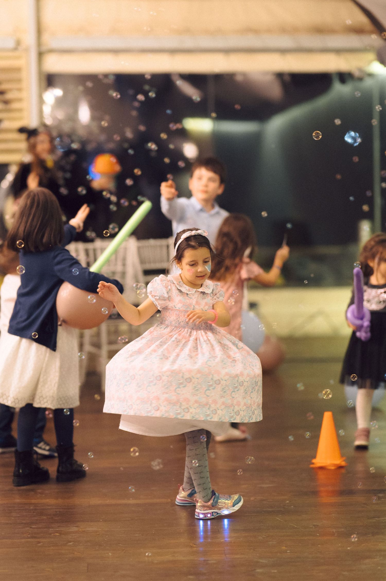 Children dancing and playing with bubble effects on wooden floor.