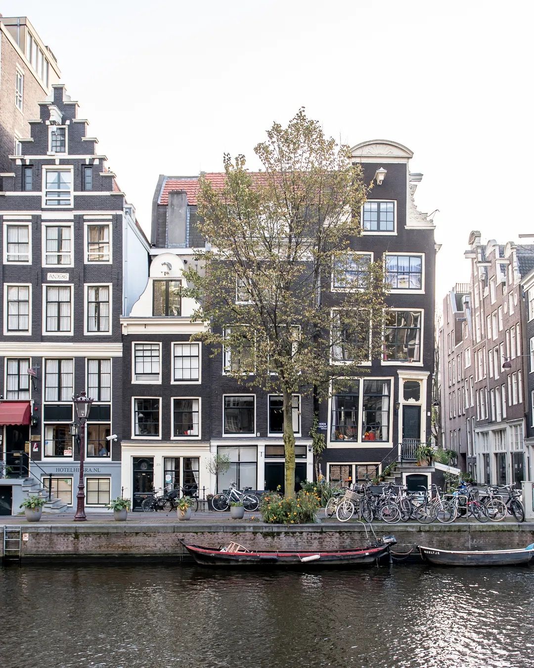 Traditional Amsterdam canal houses reflected in calm water on a peaceful autumn day.