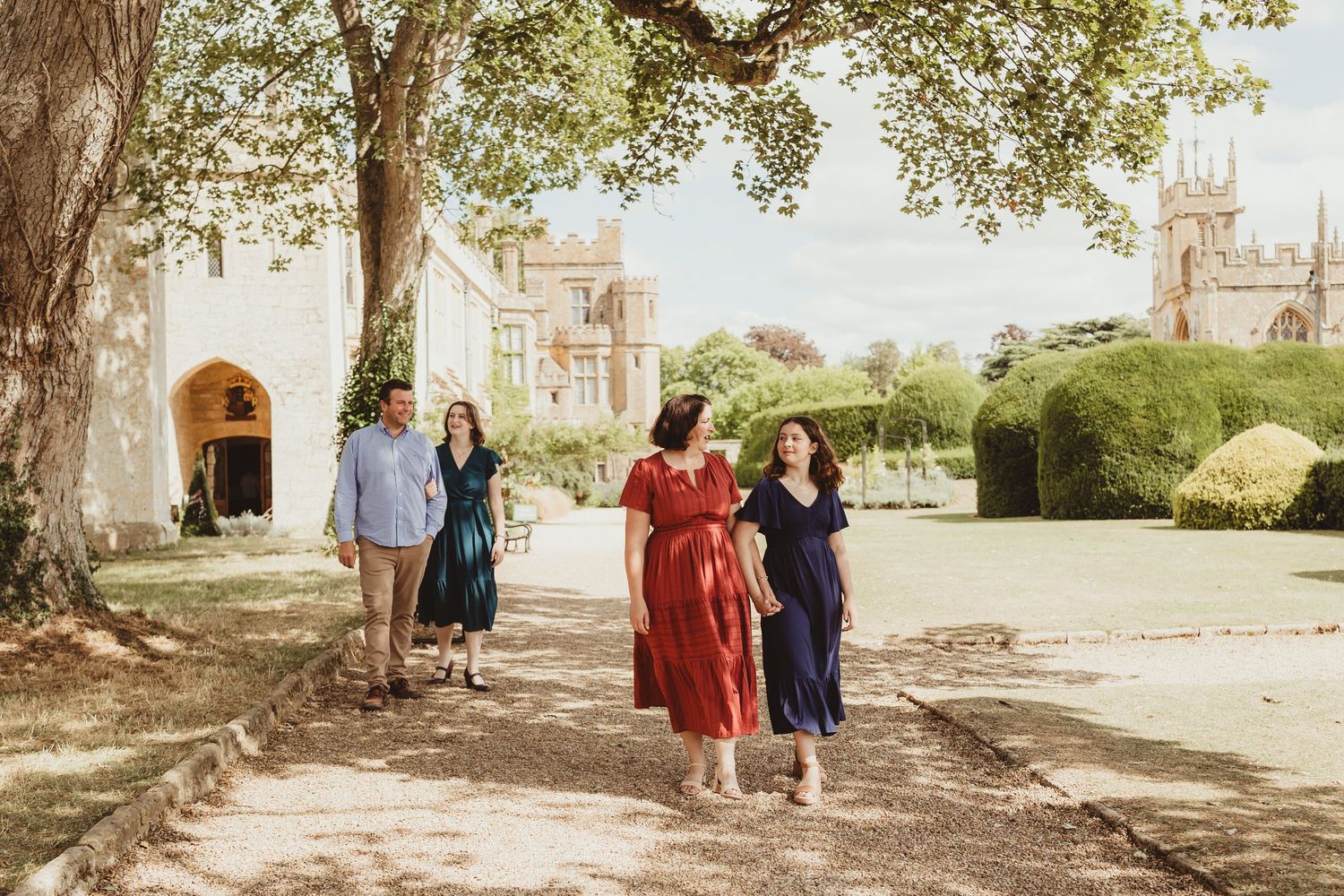 Group of people walking together on a tree-lined path during a sunny outdoor photo session.