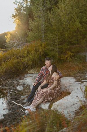 Sunset engagement photoshoot on rocky terrain surrounded by pine trees.