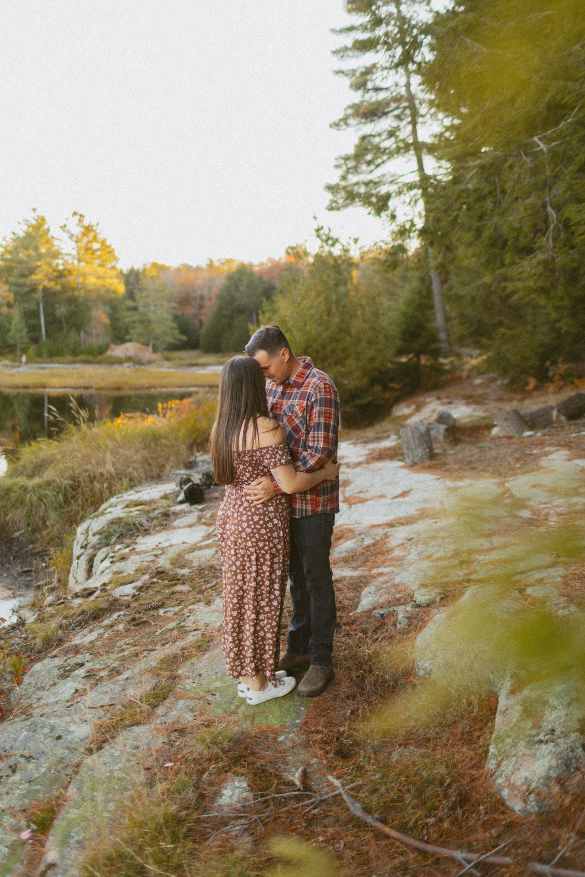 Romantic autumn photoshoot on rocky terrain with lake views at sunset.