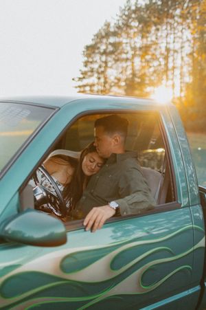 Couple sharing intimate moment in classic turquoise car at sunset.