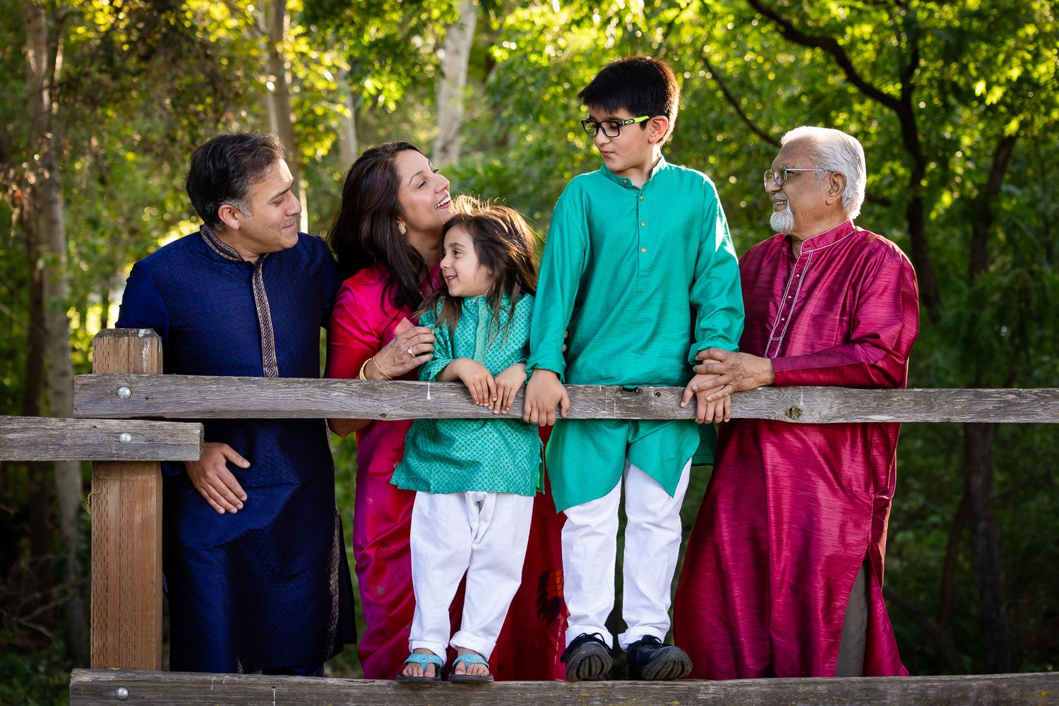 Family members stand together on a wooden fence during a family photo session at Vasona during golden hour.