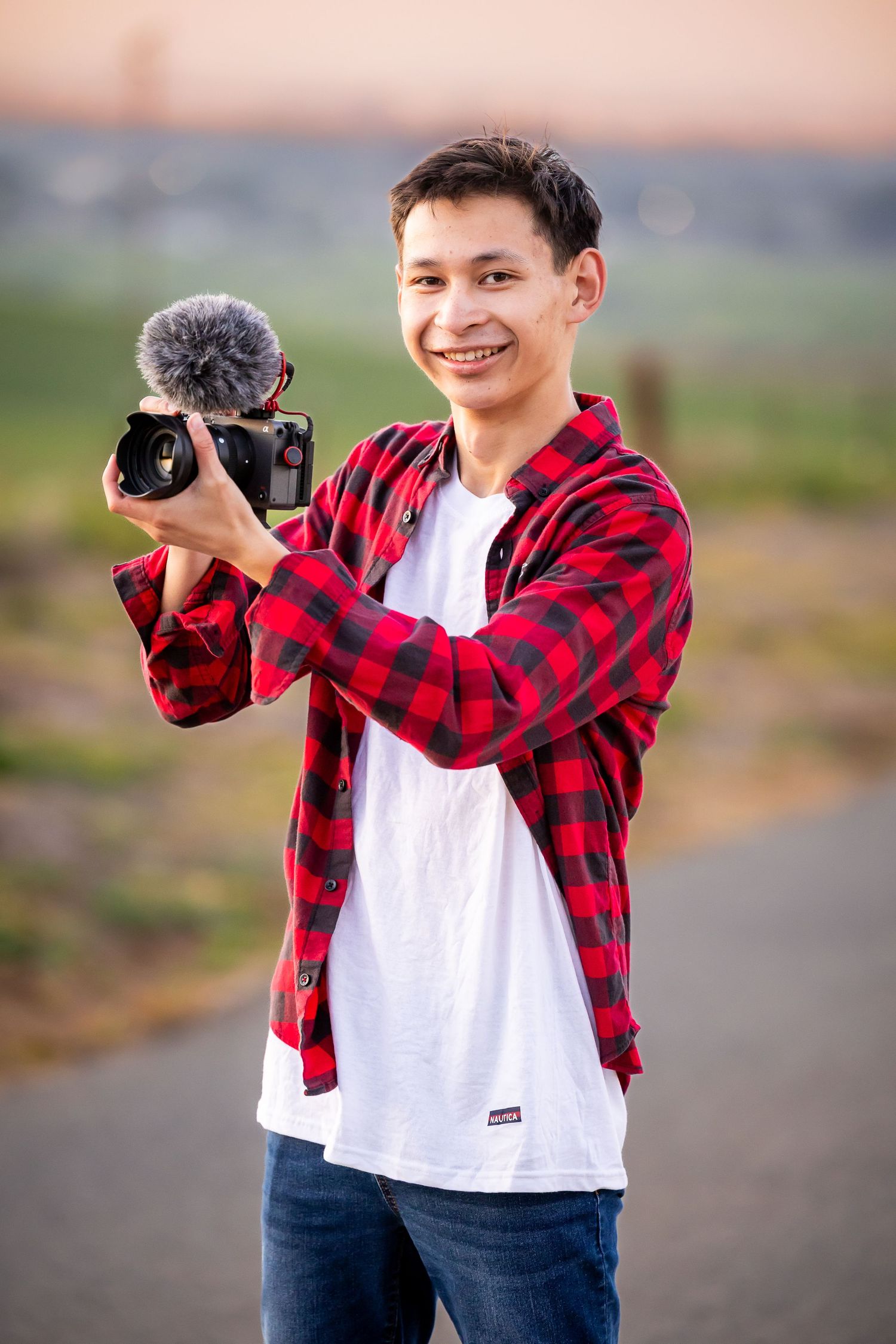 Photographer in red plaid flannel and white shirt taking photos outdoors.