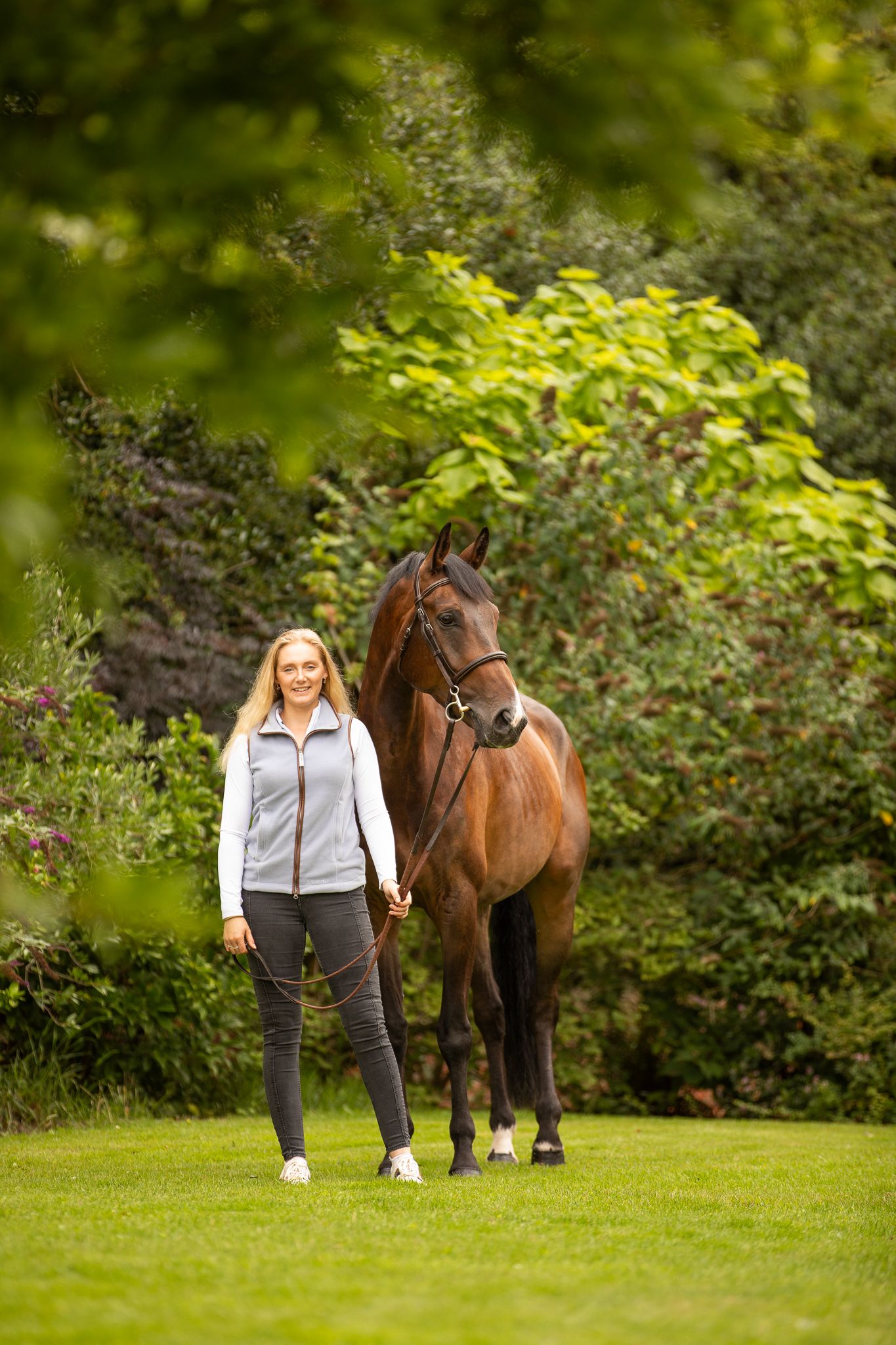 Young equestrian poses with palomino pony in a series of natural outdoor portraits showing their special bond.