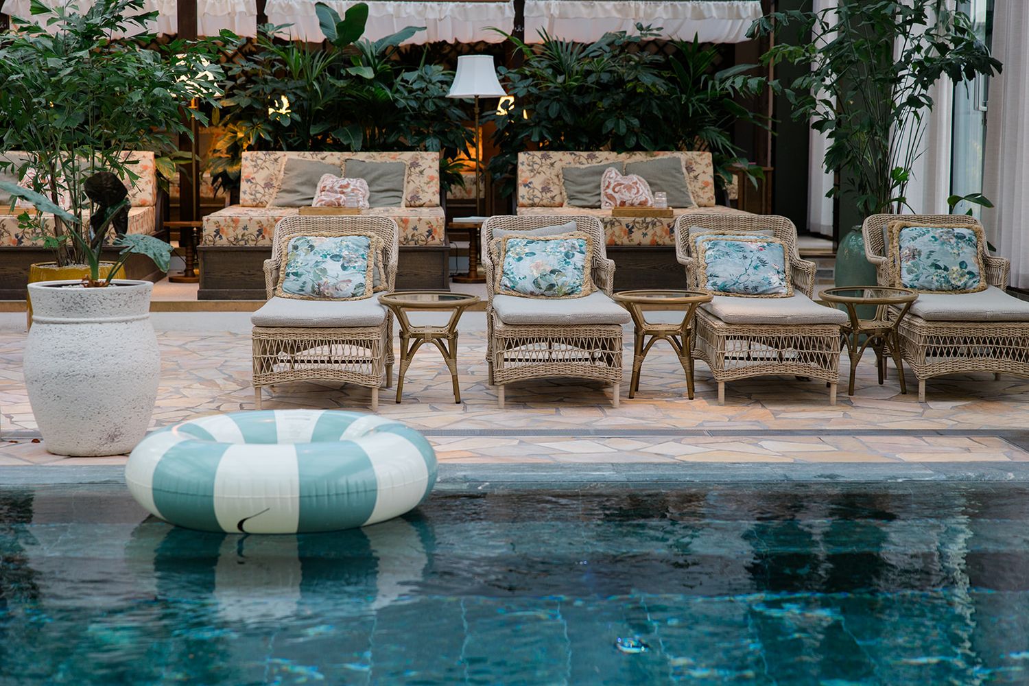 Luxury outdoor swimming pool with white lounge chairs and umbrellas arranged along the deck in a resort setting.