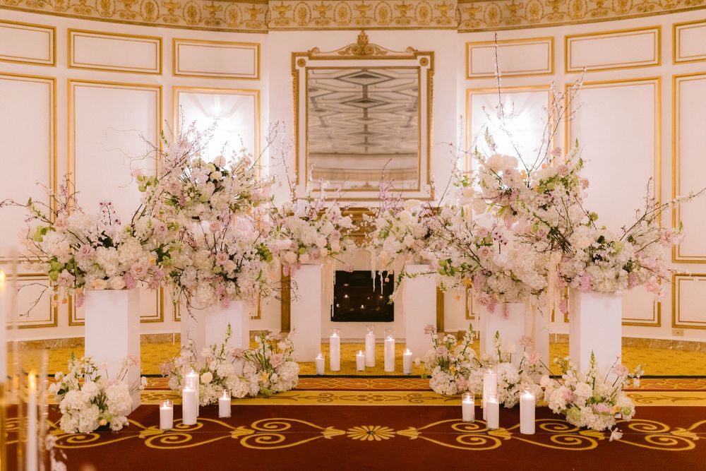 Elegant ballroom decorated with ornate gold trim and white floral arrangements for a luxurious wedding reception.