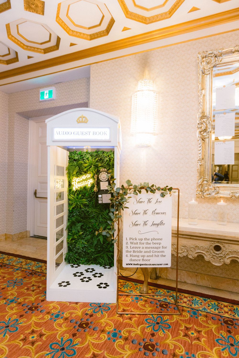 Elegant wedding venue hallway with ornate gold ceiling details, colorful floral carpet, and decorative wall signage.