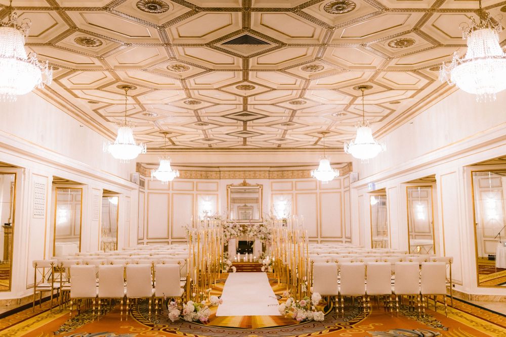 A panoramic view of an elegant white and gold ballroom with ornate ceiling details and crystal chandeliers.